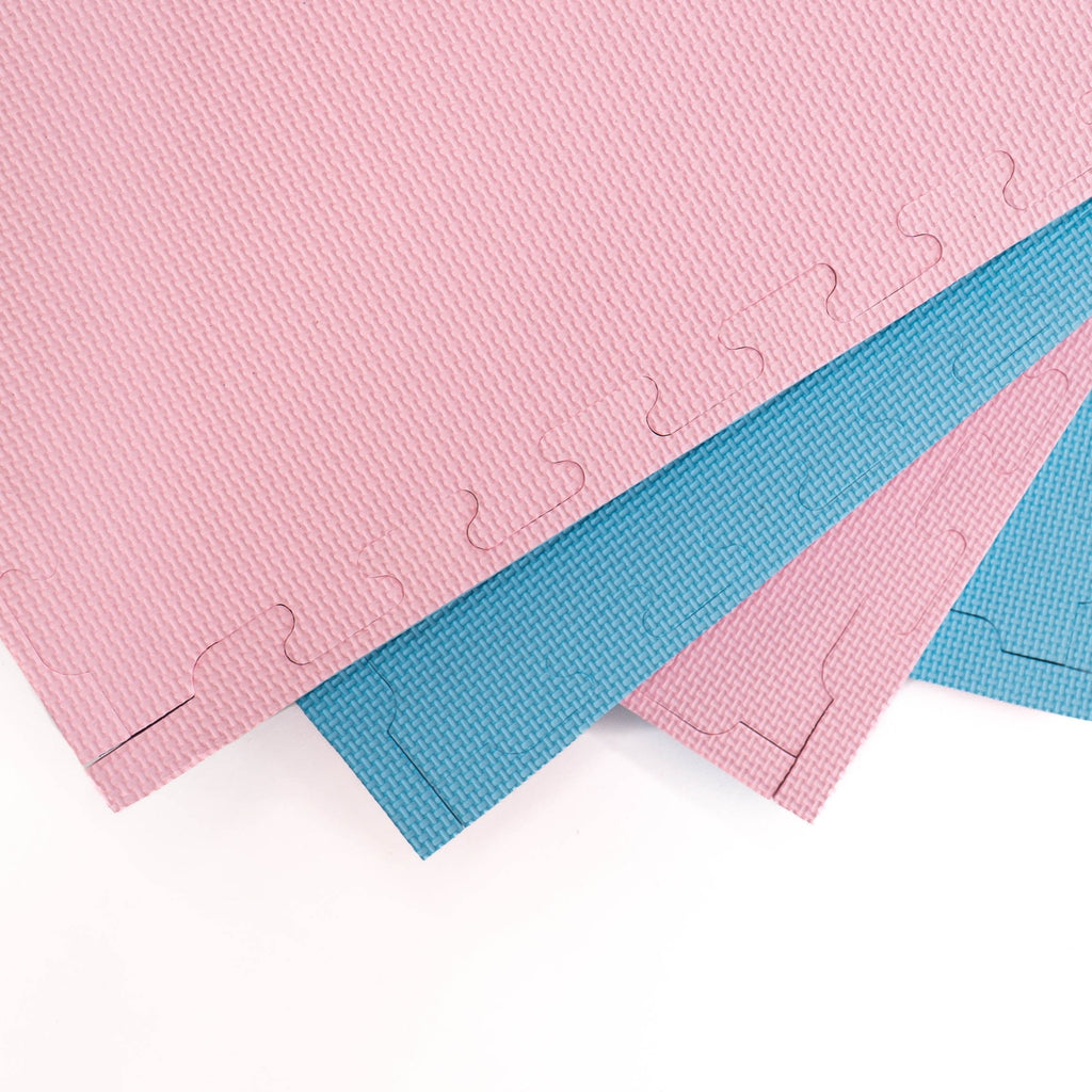 13. Close-up of overlapping foam puzzle mats in baby pink and baby blue, showing texture and interlocking edges