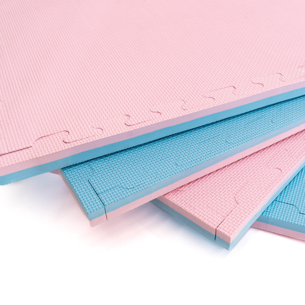 12. Close-up of stacked foam puzzle mats in baby pink and baby blue, highlighting texture and thickness
