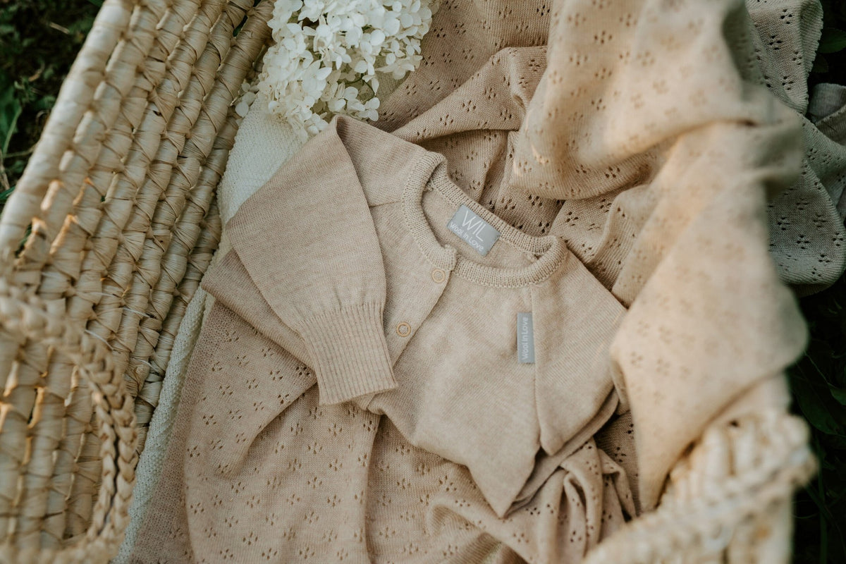 11. Beige merino wool romper and blanket set in a woven basket with flowers