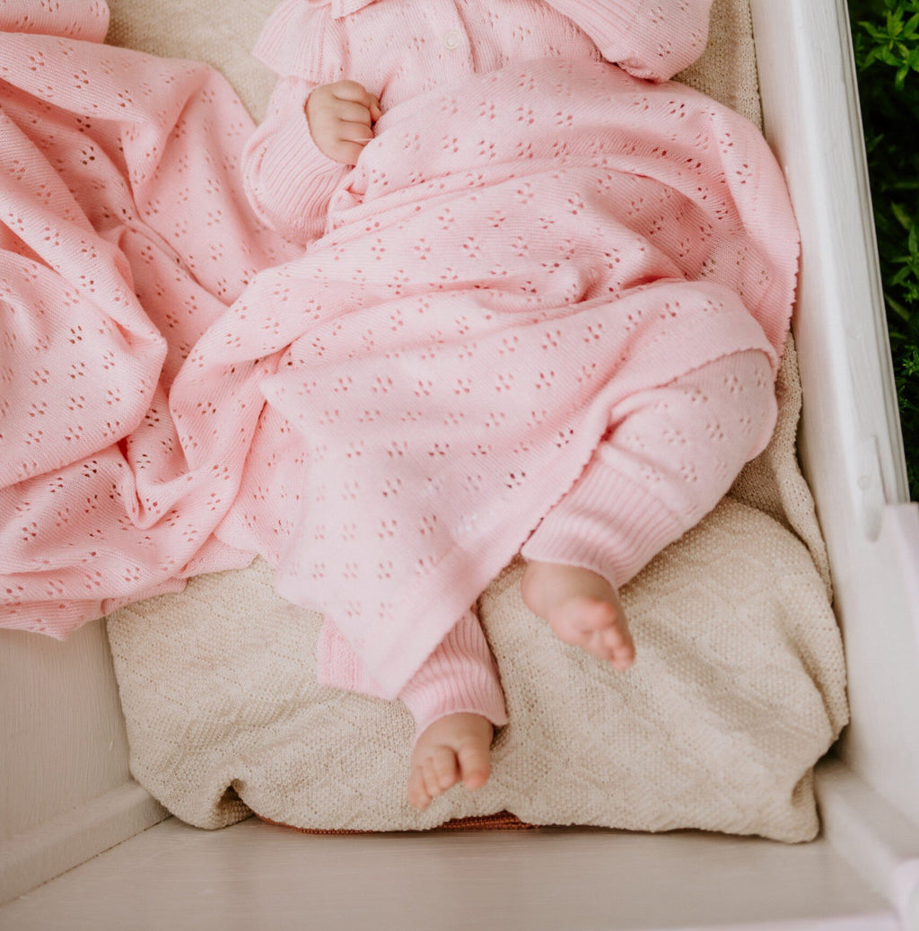 6. Baby in pink merino wool romper and blanket in a cradle