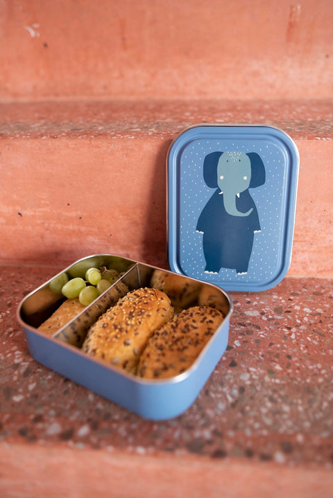 2. Blue lunch box with Mrs. Elephant illustration, open with snacks inside, placed on terracotta steps