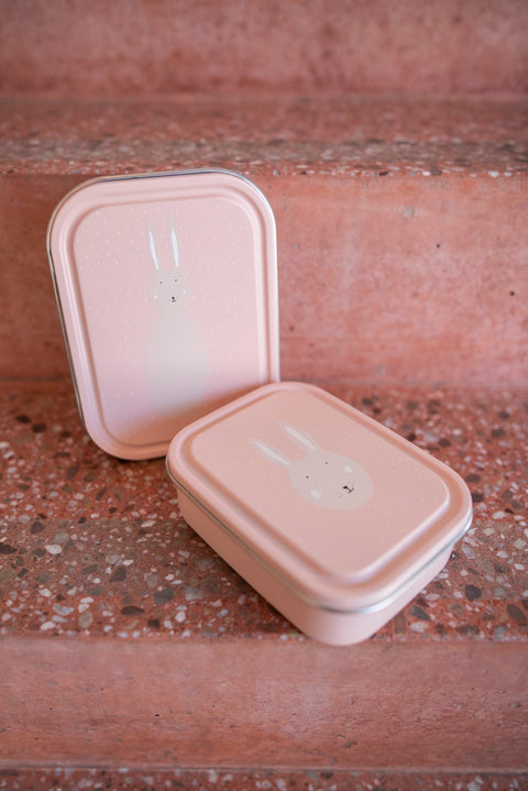 4. Two pink lunch boxes with Mrs. Rabbit illustration, stacked on terracotta steps