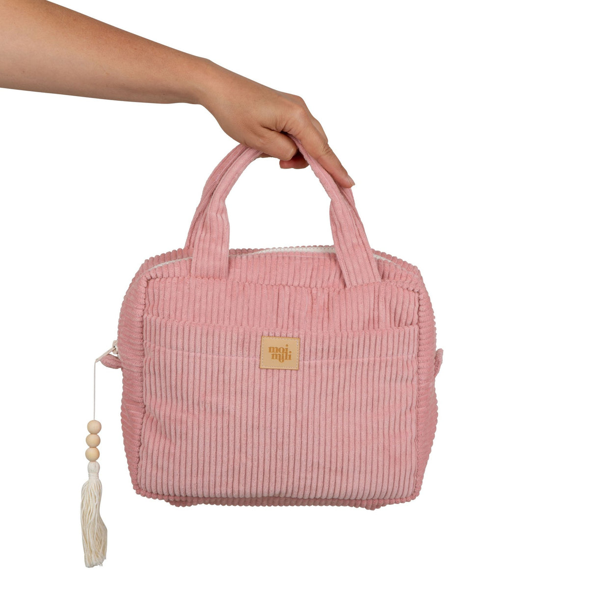 2. Hand holding baby pink makeup bag with handles and Moi Mili logo, showing size and design