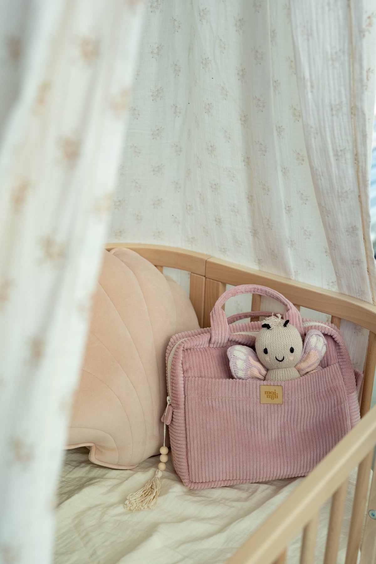 1. Moi Mili baby pink makeup bag in a crib with plush toy and canopy