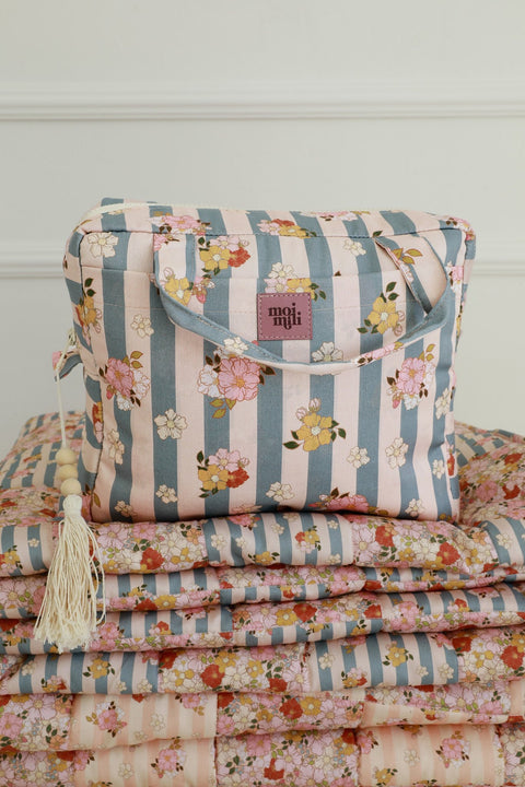 4. Blue striped makeup bag with floral print and Moi Mili logo, placed on matching floral fabric stack