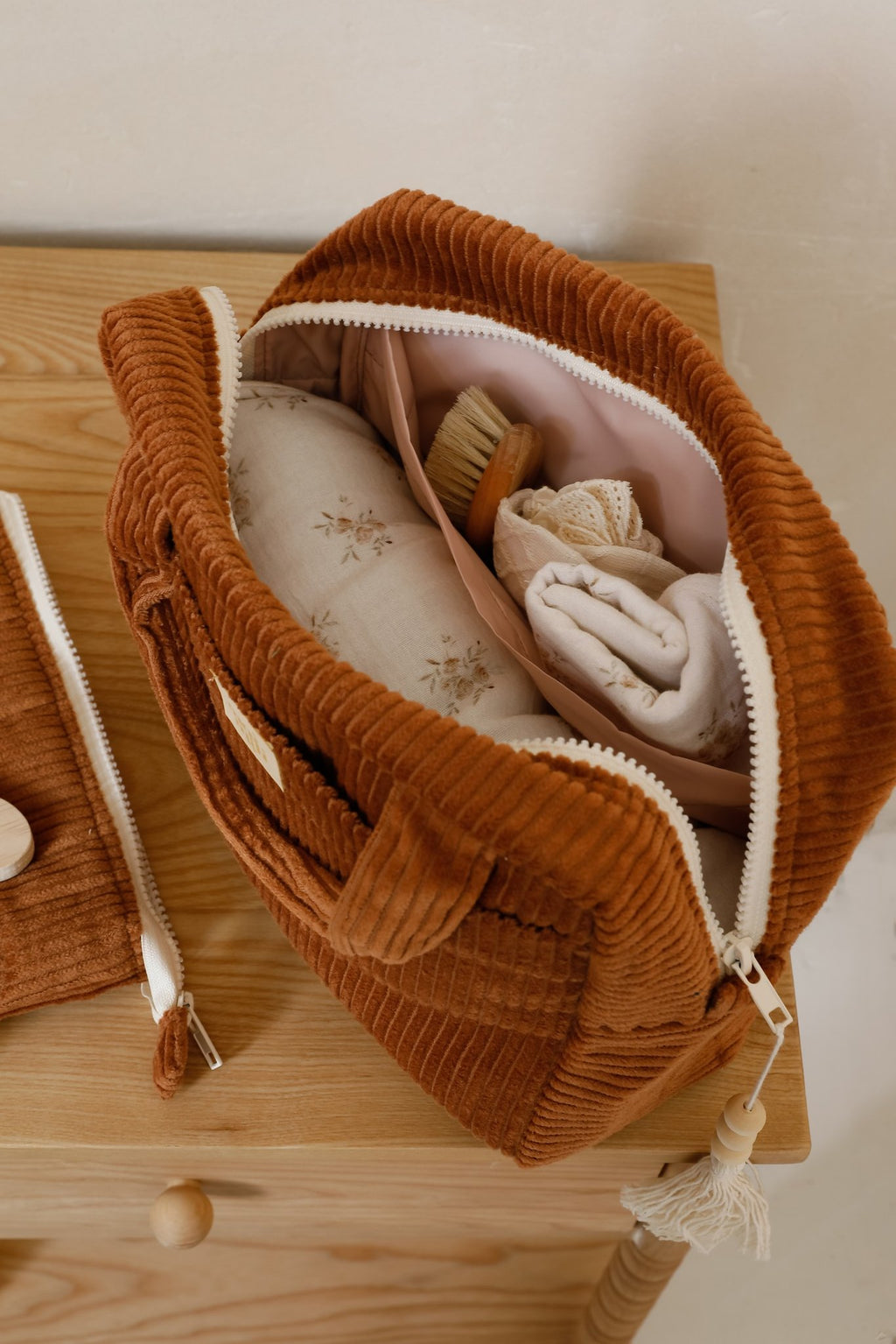7. Large caramel makeup bag open, showing interior with toiletries and pink lining, placed on wooden surface