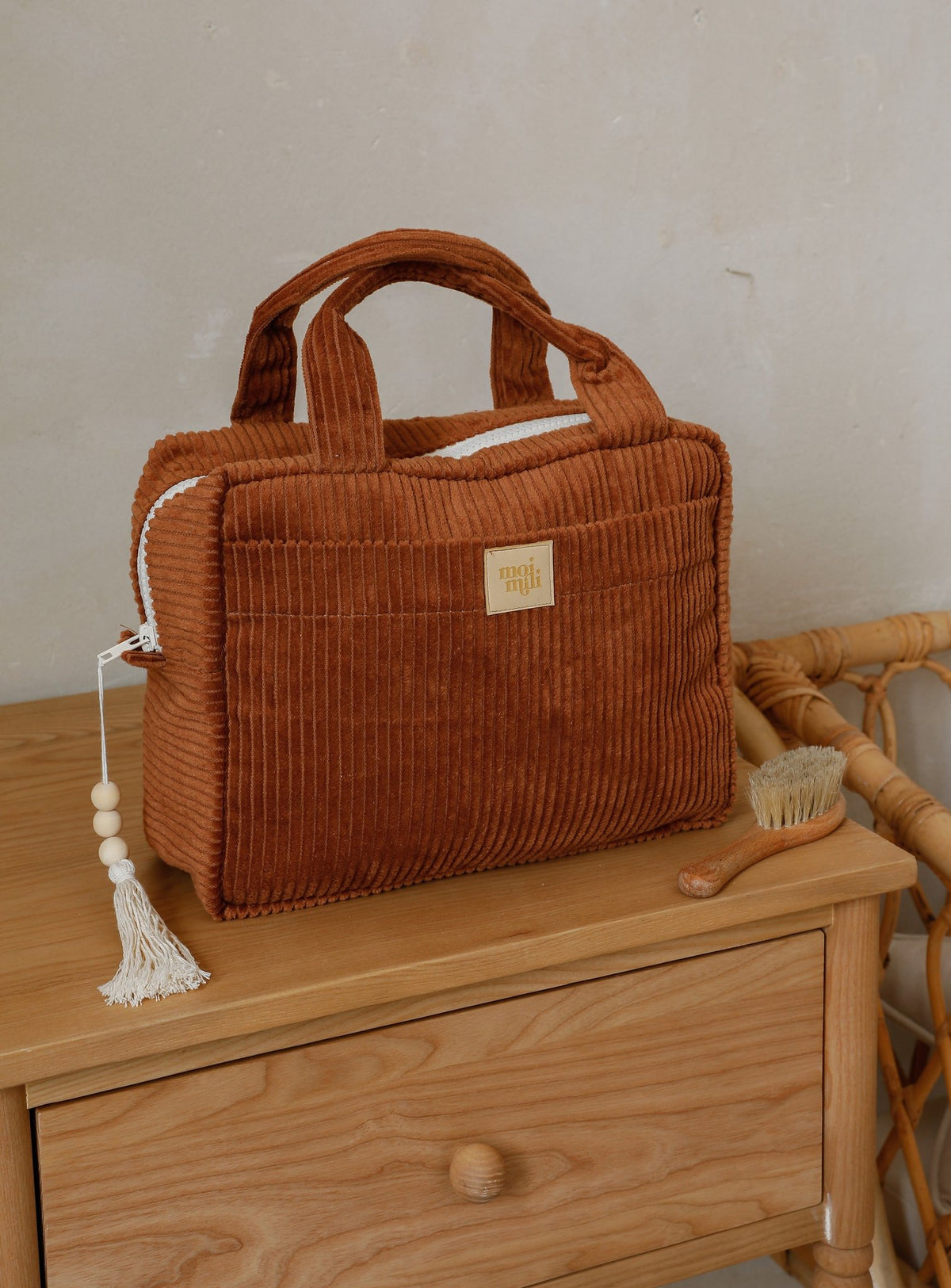 2. Caramel large makeup bag with tassel detail on a wooden dresser, highlighting its corduroy texture and front pocket