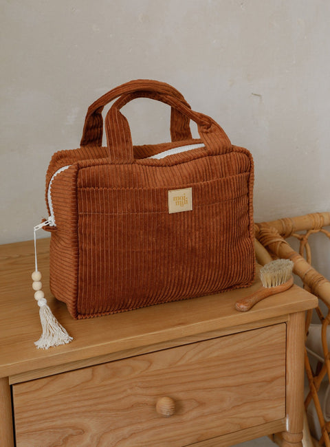 2. Large caramel makeup bag with handles and tassel, placed on a wooden dresser with a brush beside it