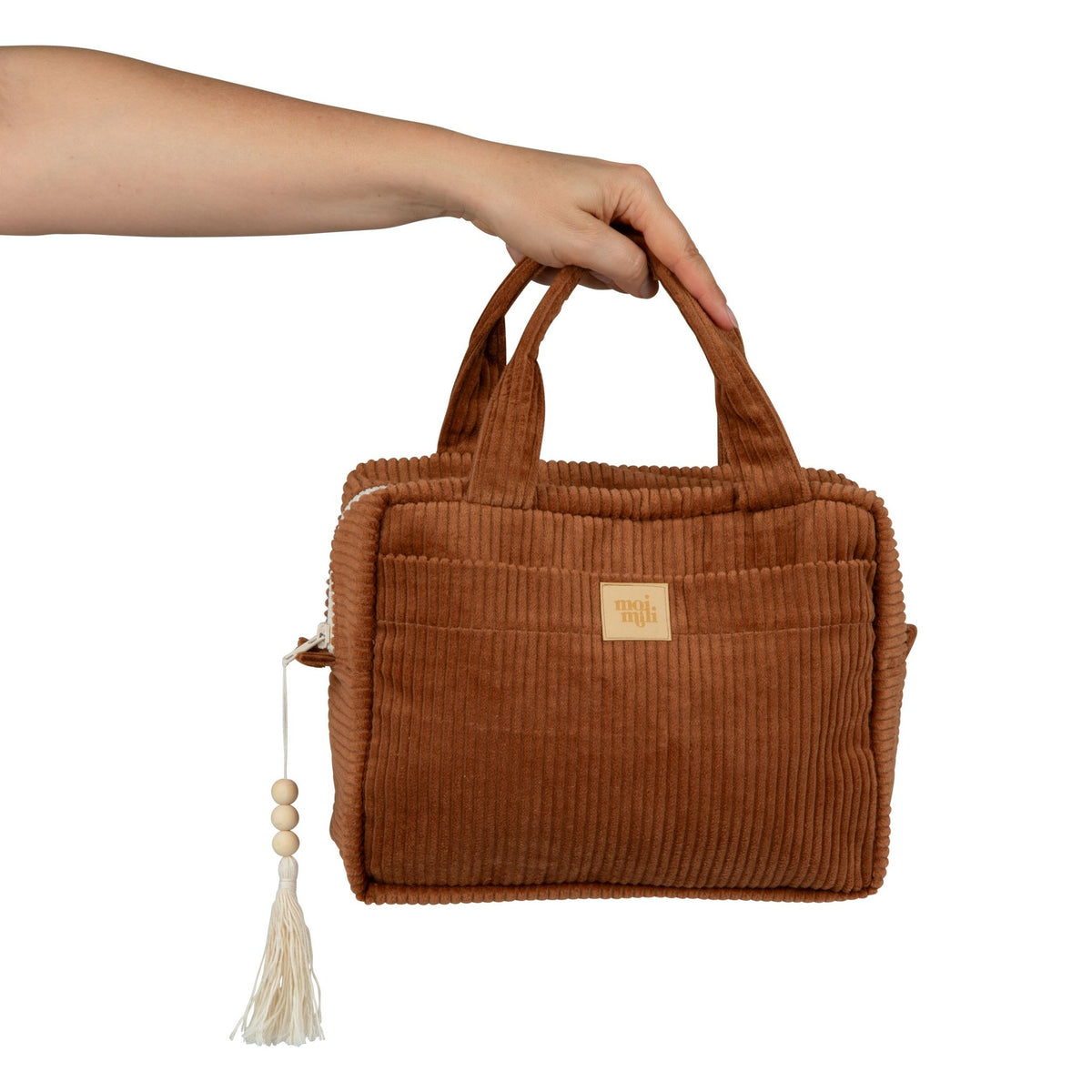 4. Hand holding caramel large makeup bag with tassel, displaying its portable size and corduroy texture