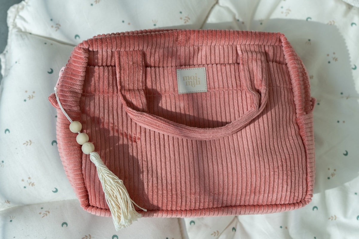 6. Close-up of coral makeup bag with tassel on quilted fabric