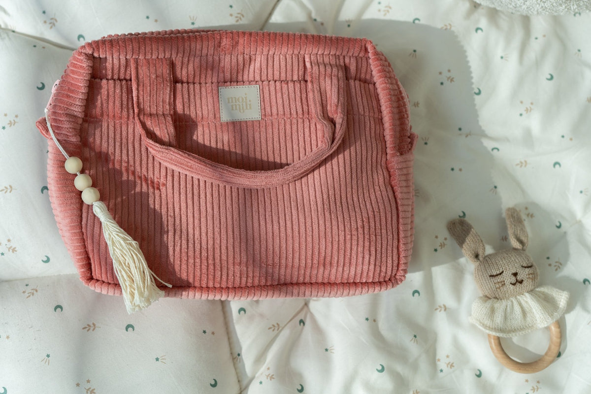 4. Coral makeup bag with tassel on patterned fabric, next to plush toy