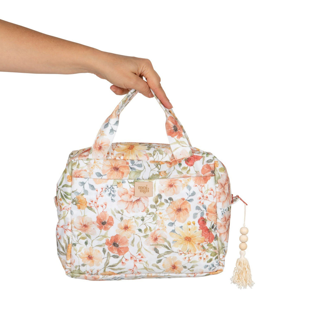 1. Hand holding large floral makeup bag with orange and green flower design and tassel zipper pull