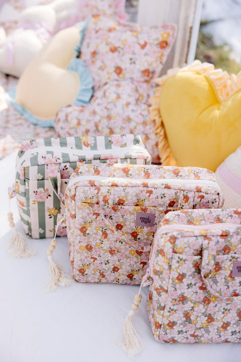 1. Three Moi Mili makeup bags with different prints displayed on outdoor setting with cushions