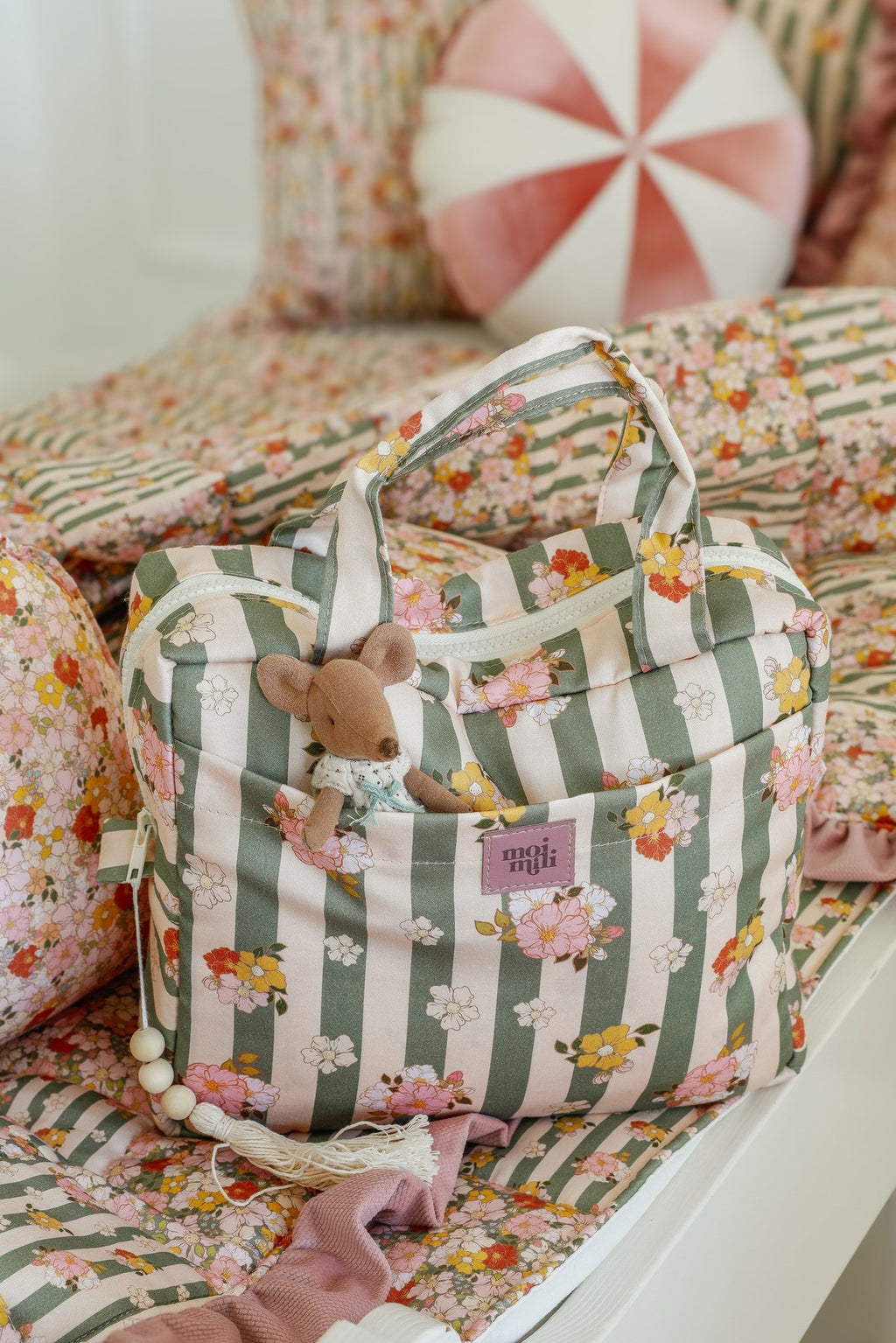 3. Green striped large make-up bag with floral pattern and toy mouse in outer pocket on a floral bedspread