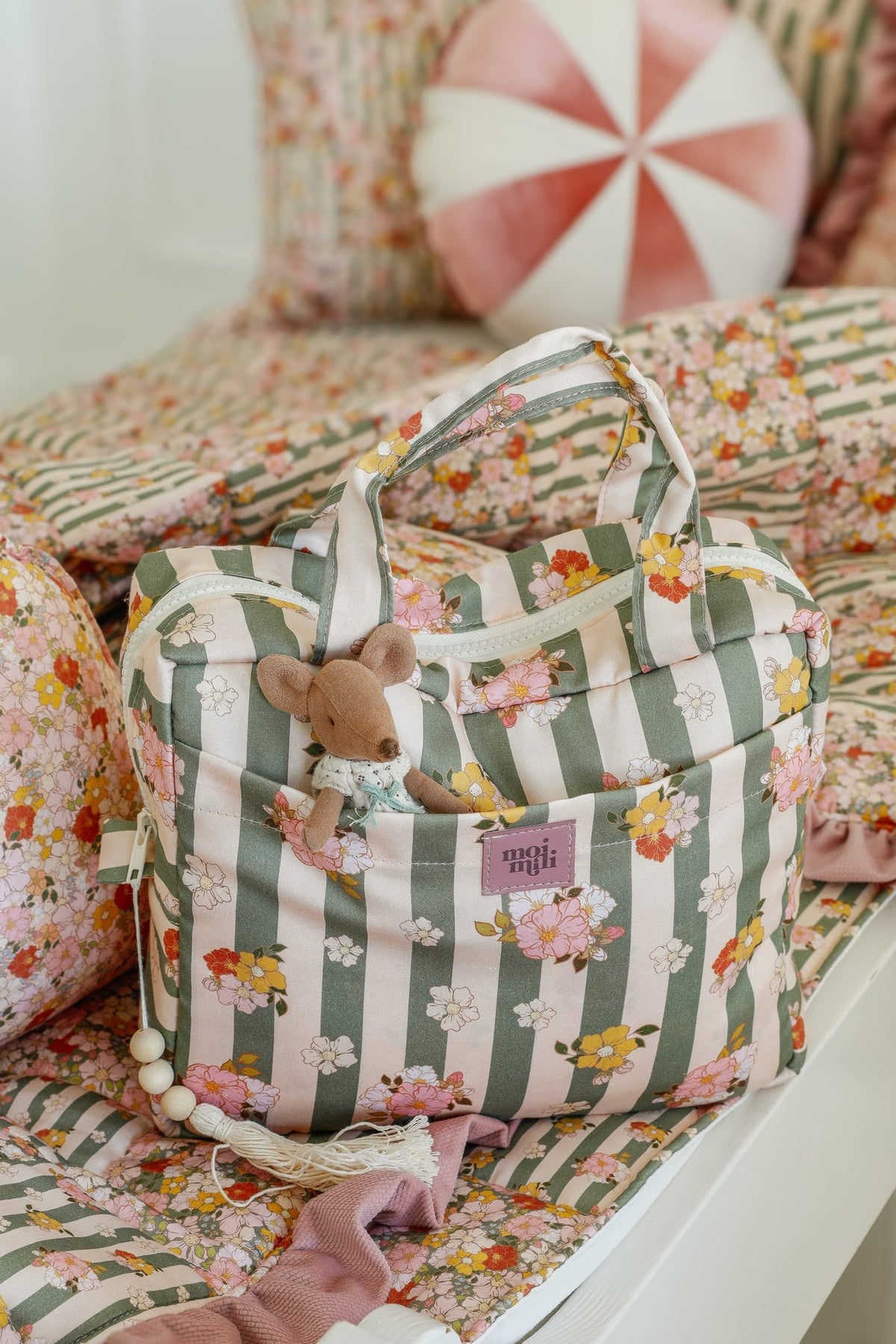 3. Green striped large make-up bag with floral pattern and toy mouse in outer pocket on a floral bedspread