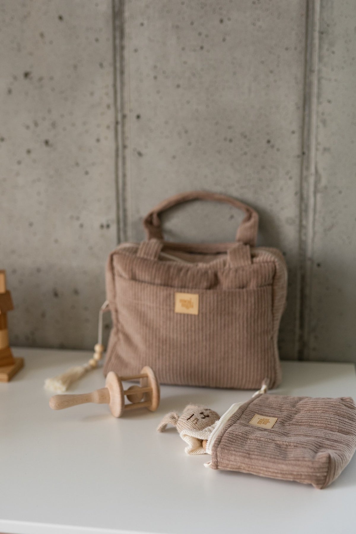 1. Latte-colored makeup bag with ribbed texture and Moi Mili logo, styled with wooden toys on a white surface