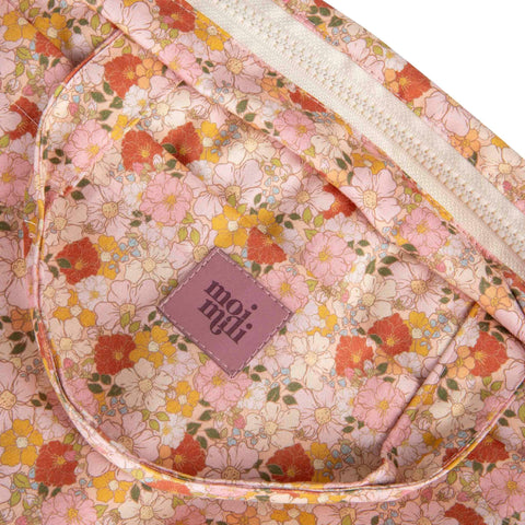3. Close-up of Moi Mili logo on floral print cotton fabric with pink, orange, and yellow flowers