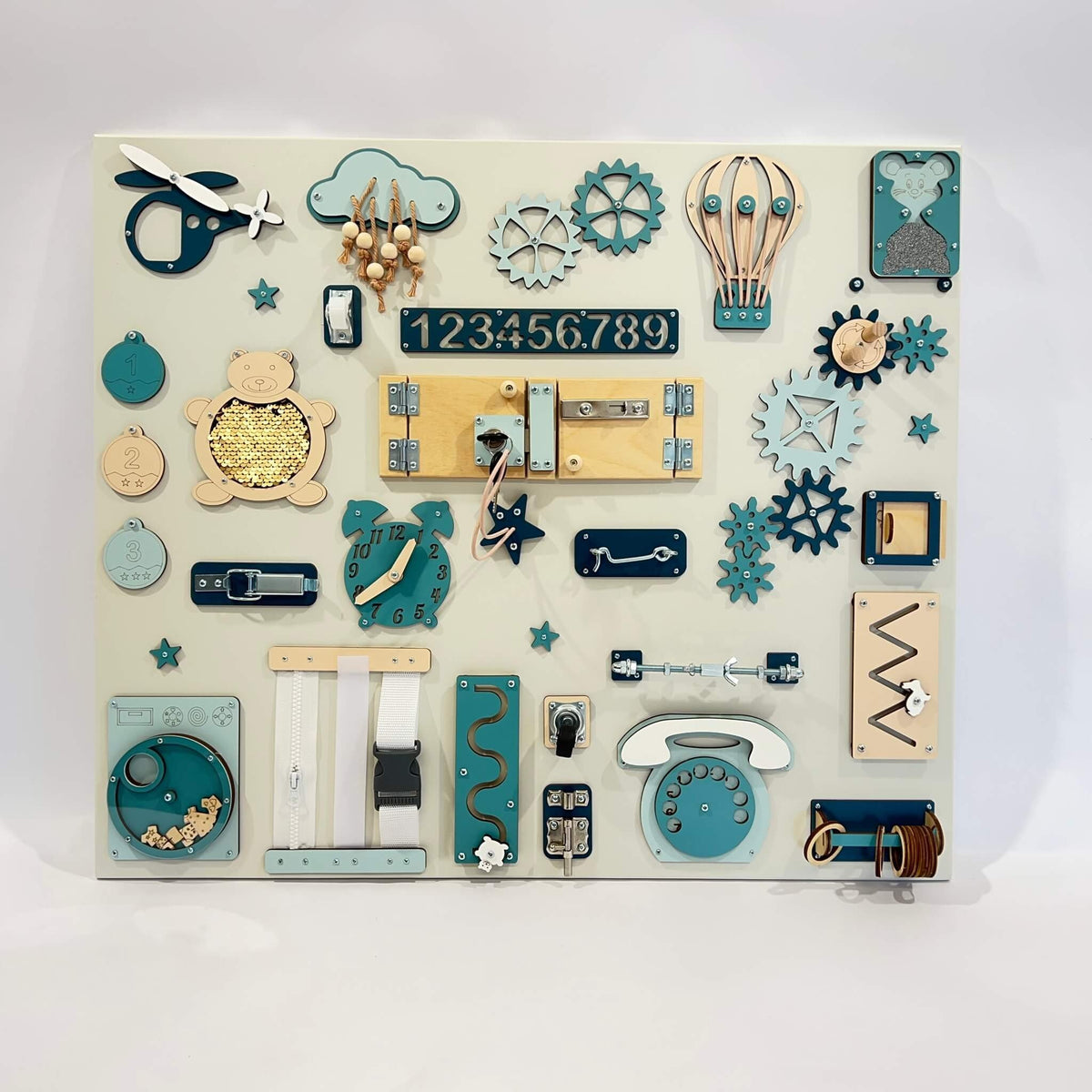1. Large Montessori busy board with various interactive elements in blue and beige tones, designed for children's learning and play, shown in a studio setting.