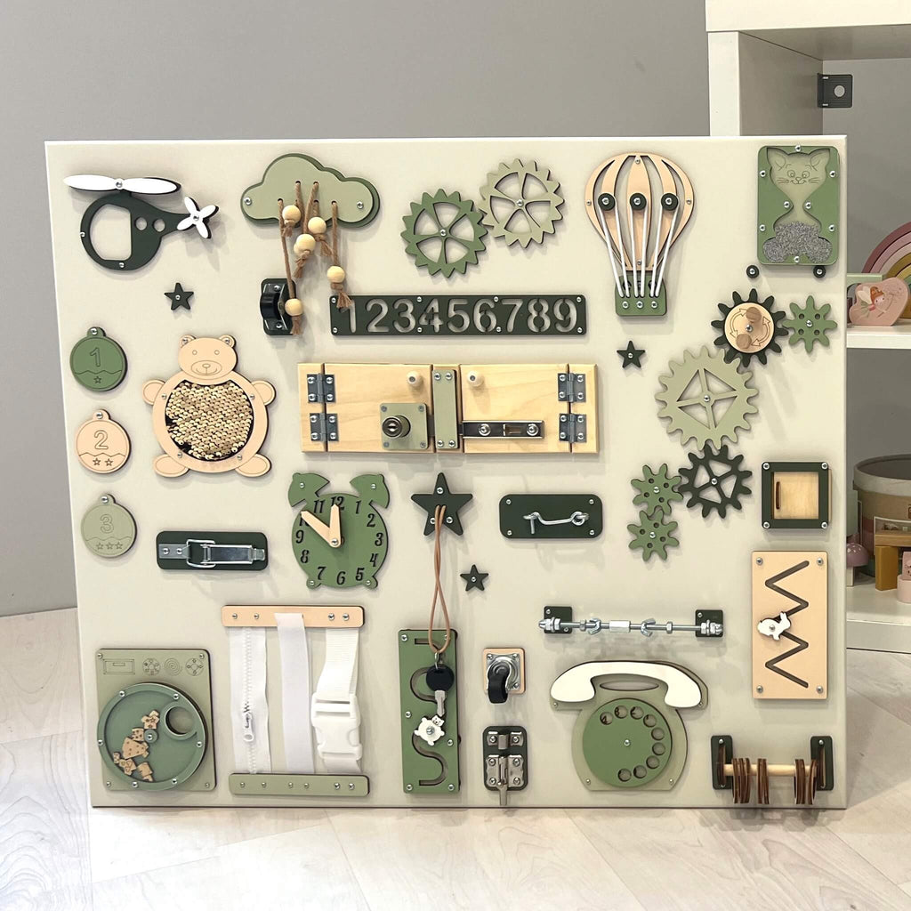 2. Large Montessori busy board featuring green and beige interactive elements, displayed in a child's playroom setting.