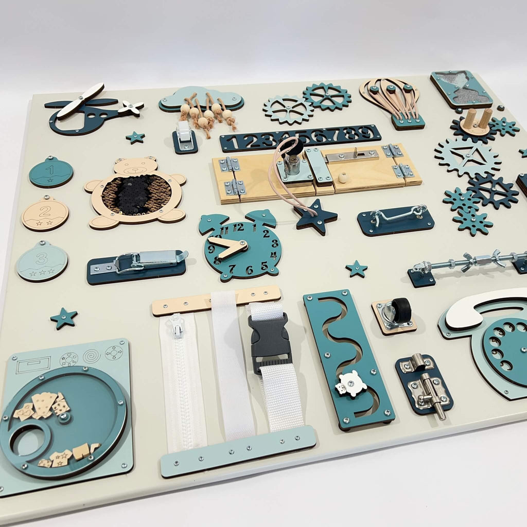 6. Flat lay of Montessori busy board with blue and beige elements, displaying various interactive features for children's learning.