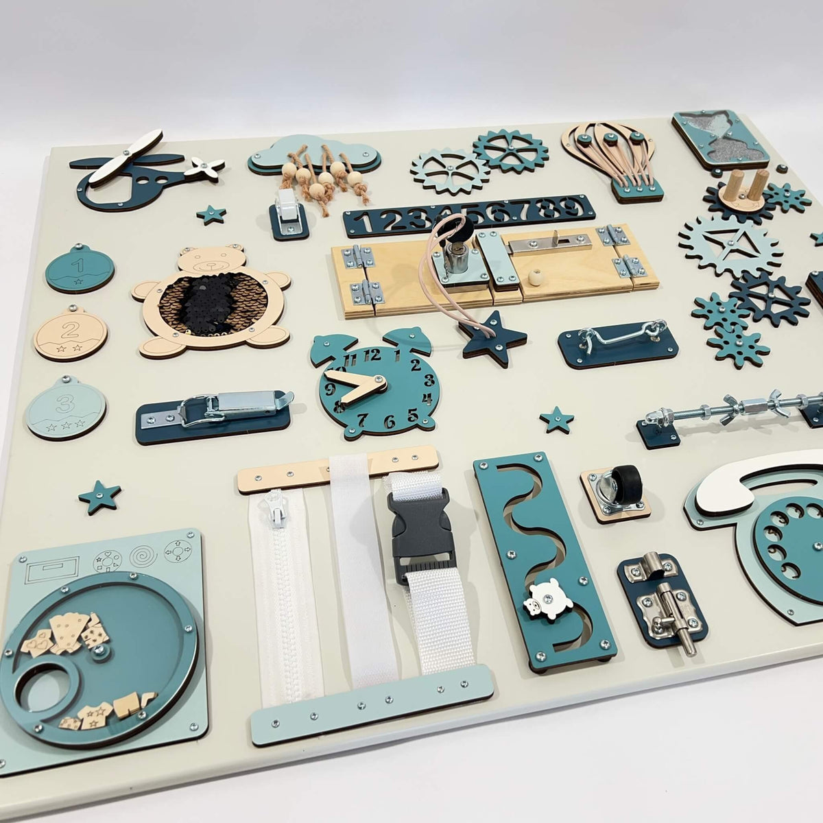 6. Flat lay of Montessori busy board with blue and beige elements, displaying various interactive features for children's learning.