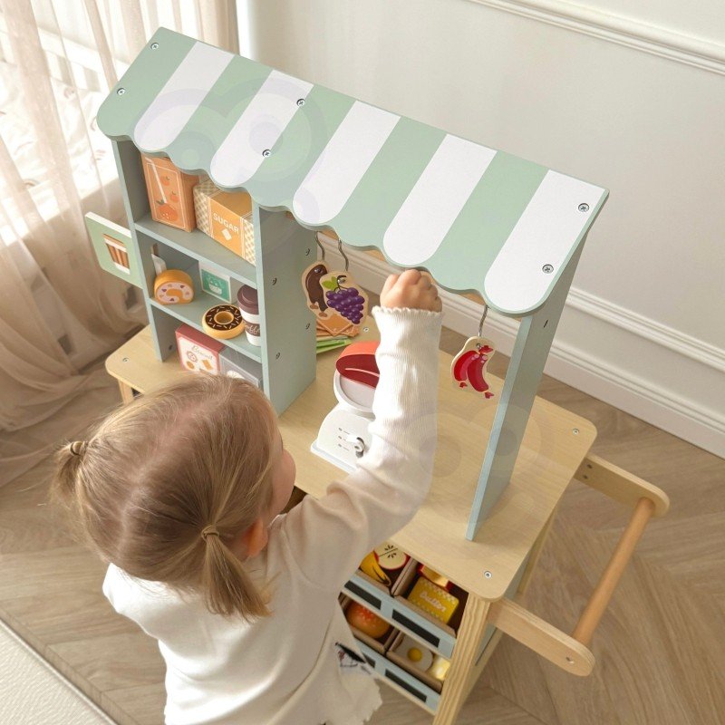 18. Child reaching for hanging play food on Woopie Green wooden food truck stand
