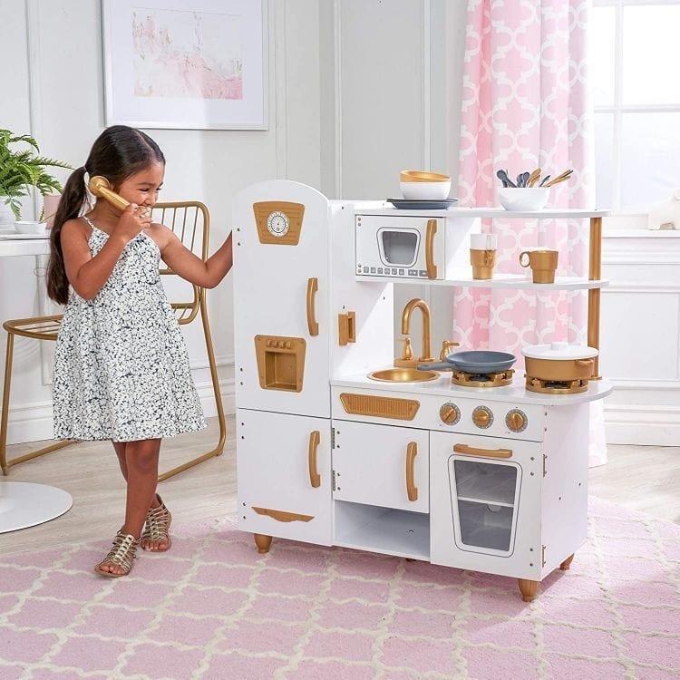 1. Girl playing with Angelove white and gold wooden play kitchen in a stylish room with pink accents