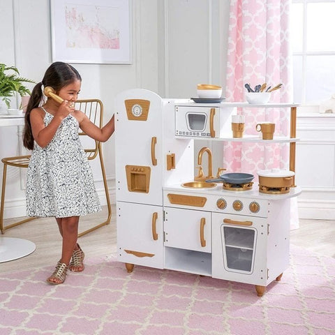 1. Girl playing with Angelove white and gold wooden play kitchen in a stylish room with pink accents