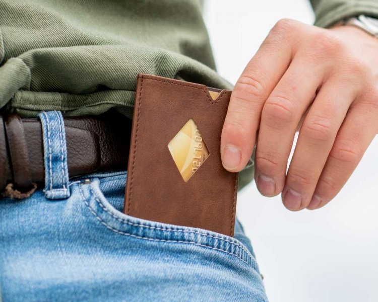 14. Person placing EXENTRI City hazelnut cardholder into jeans pocket