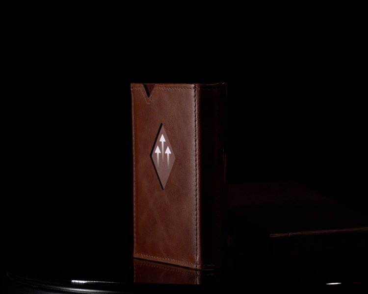 14. Brown EXENTRI Miniwallet standing upright on a dark reflective surface