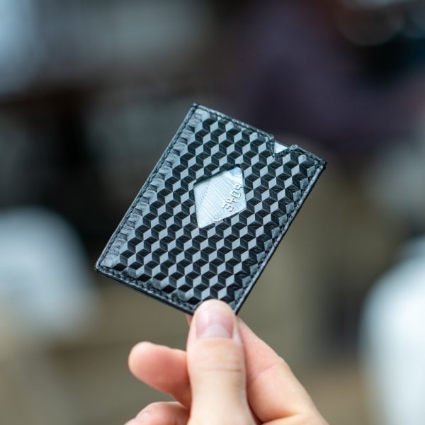 1. Hand holding EXENTRI City black cardholder with cube pattern in outdoor setting