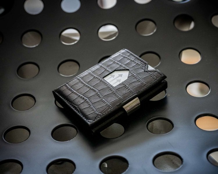 1. Black EXENTRI trifold wallet with textured pattern on perforated metal surface