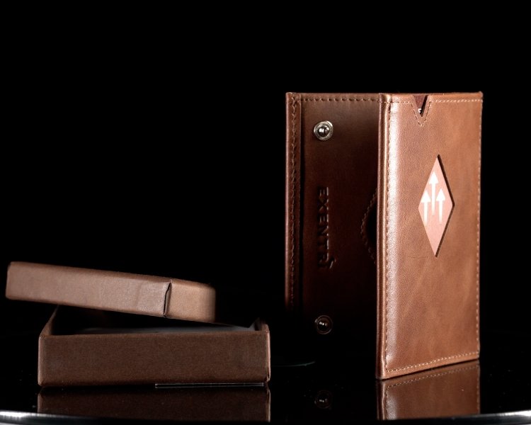 8. Brown EXENTRI Miniwallet standing upright with open box on reflective surface