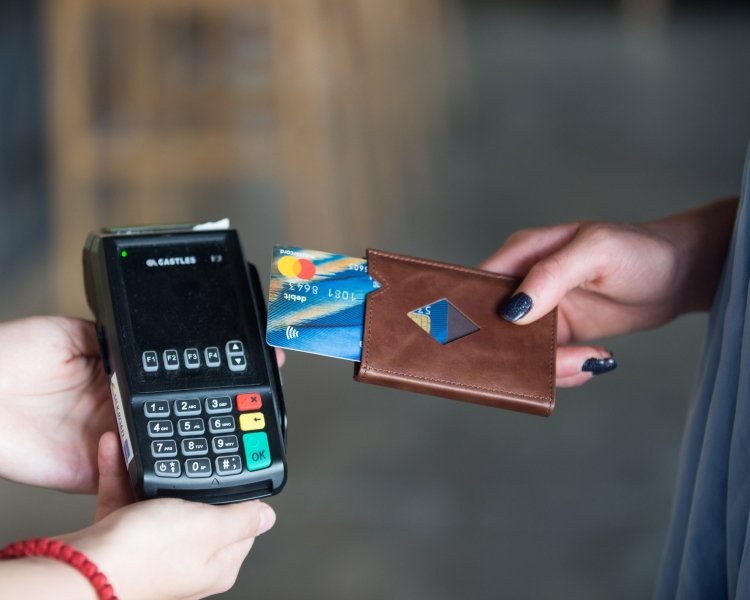 7. Person using brown EXENTRI Miniwallet to pay with a card at a terminal