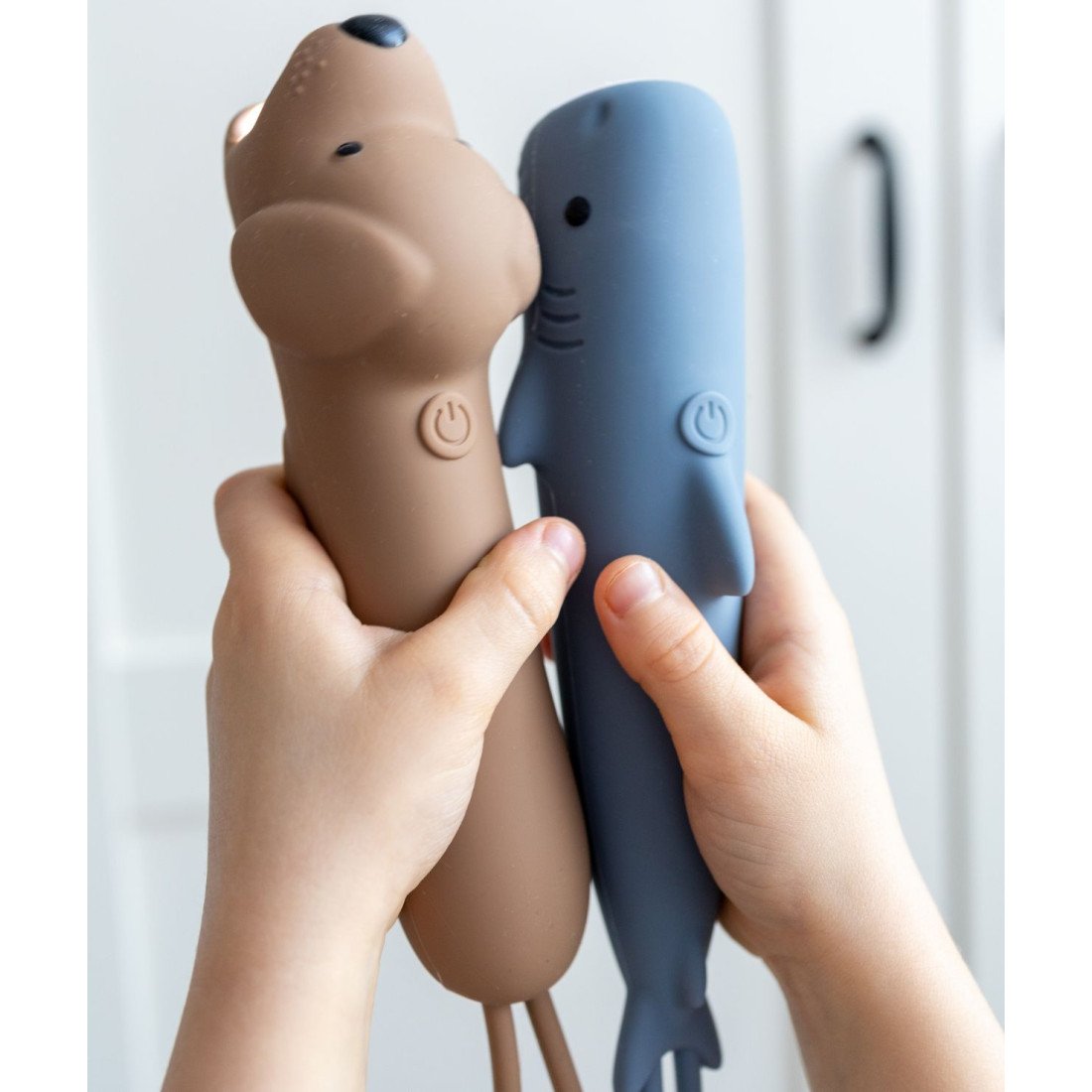 5. Child holding brown dog and blue shark-shaped silicone flashlights, highlighting playful design and functionality.