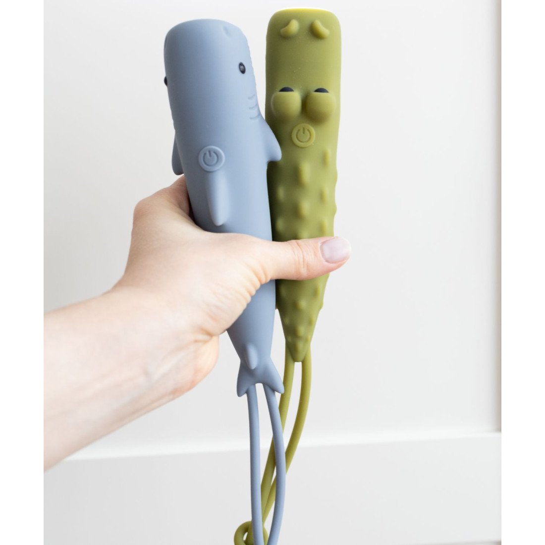 1. Hand holding two animal-shaped flashlights in blue and green against white background