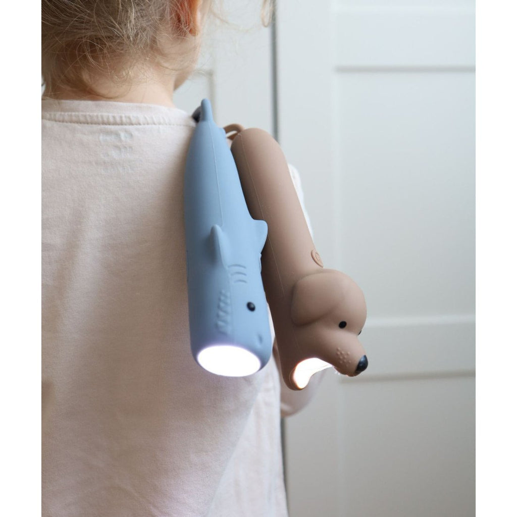 7. Child wearing blue shark and brown dog-shaped silicone flashlights over shoulder, illustrating portability and ease of use.
