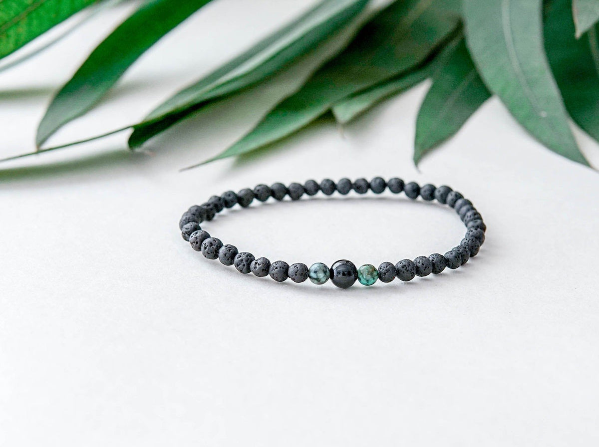 3. Men's lava bracelet with onyx and turquoise beads by Canary Lava, displayed with green leaves