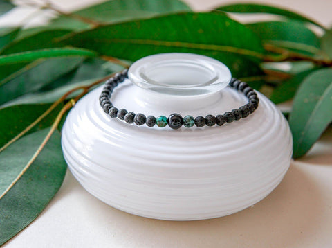 4. Close-up of men's lava bracelet with onyx and turquoise beads by Canary Lava on white dish