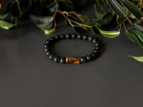 4. Close-up of men's lava bracelet with 8mm tiger eye bead by Canary Lava on dark surface with greenery