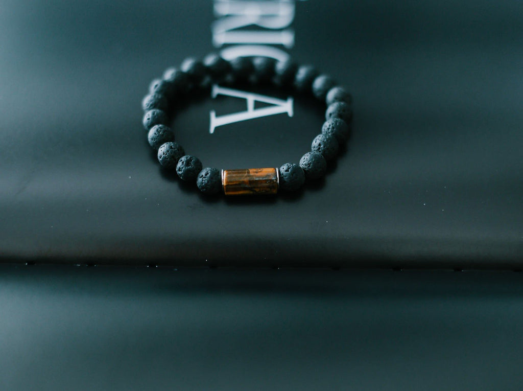 2. Studio shot of men's lava bracelet with 8mm tiger eye bead by Canary Lava on black background