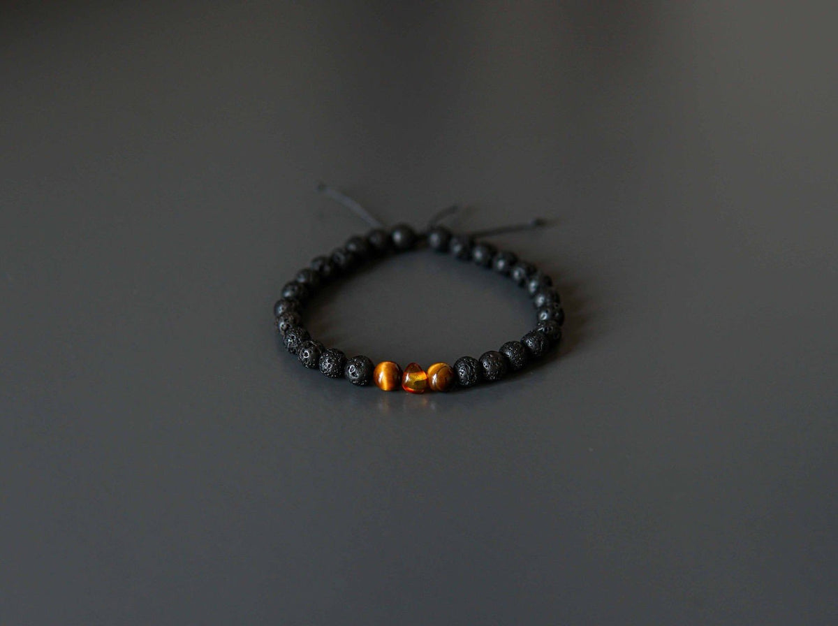 5. Flat lay of Canary Lava Stone Bracelet with Amber and Tiger Eye beads on dark surface