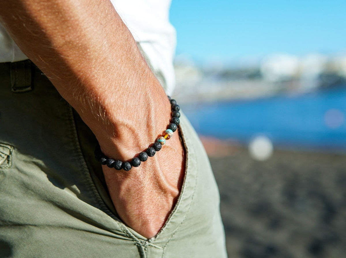 1. Men's lava stone bracelet with amber and turquoise accents by Canary Lava, worn on wrist at the beach