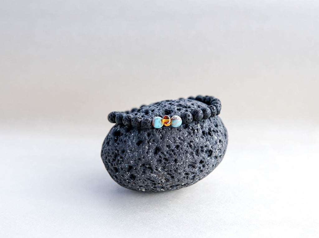 5. Close-up of Canary Lava stone bracelet with amber and turquoise, resting on a lava rock