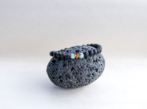 5. Close-up of Canary Lava stone bracelet with amber and turquoise, resting on a lava rock