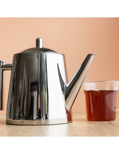 1. La Cafetière silver stainless steel jug with infuser next to a glass of tea on a wooden table against a peach background