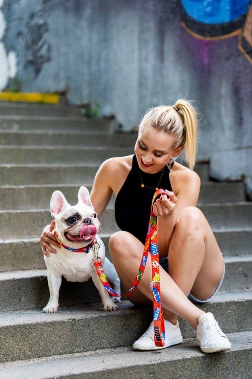 1. Woman sitting on steps with a French Bulldog, holding a red graffiti dog leash