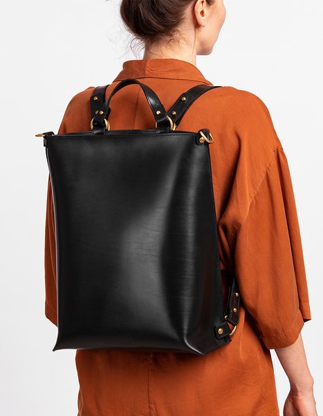 2. Woman wearing black leather backpack by Stella Soomlais over orange shirt, shown from back