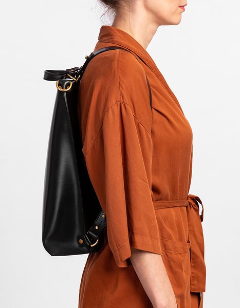 3. Woman carrying black leather backpack by Stella Soomlais on shoulder, wearing orange shirt