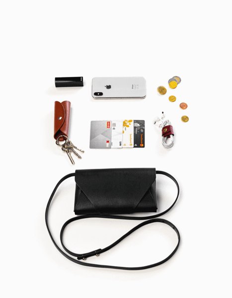 6. Flat lay of black leather Stella Soomlais Capital of Plenty clutch-wallet with contents including phone and cards